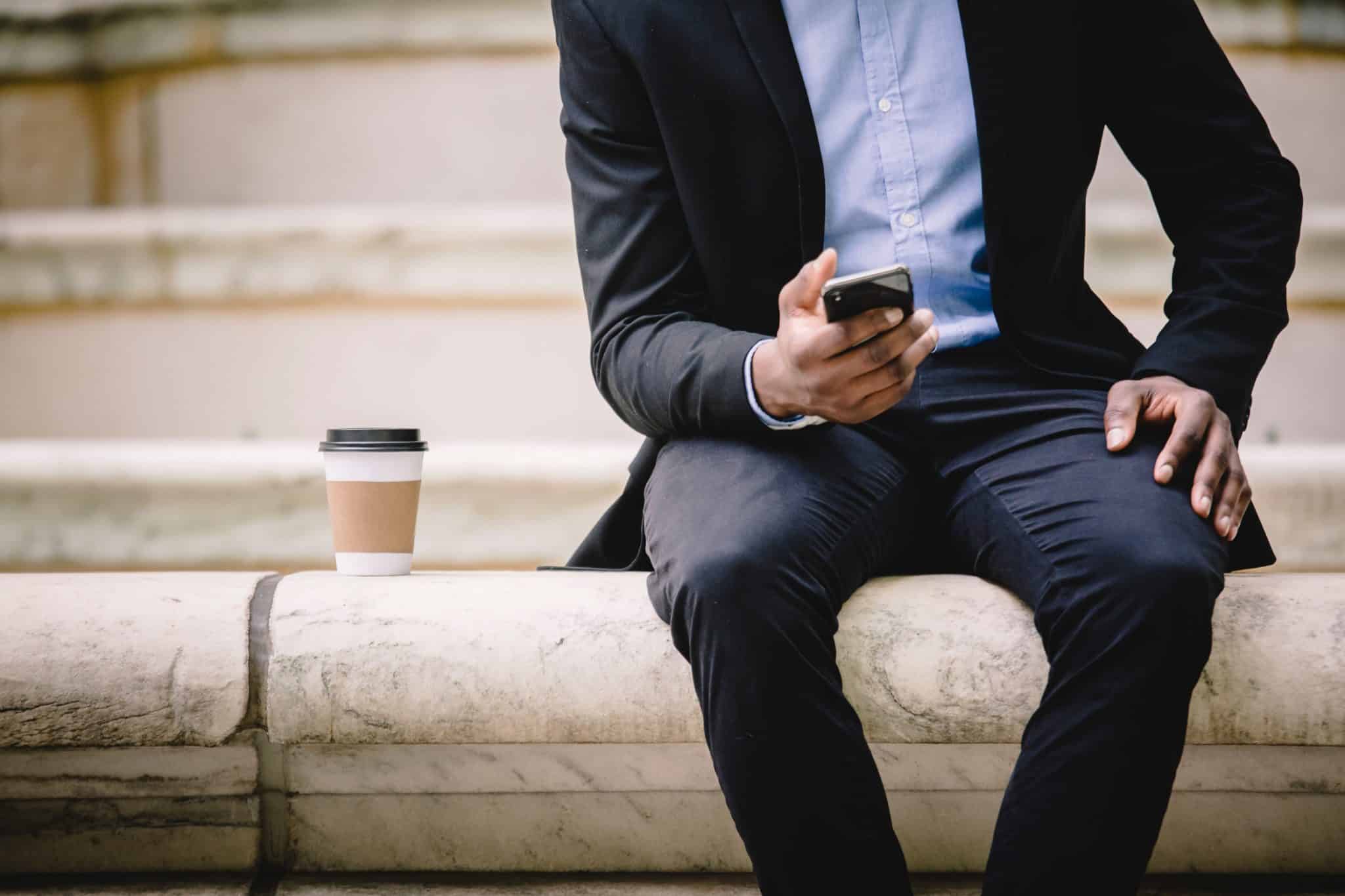 Businessman using smartphone while sitting on steps