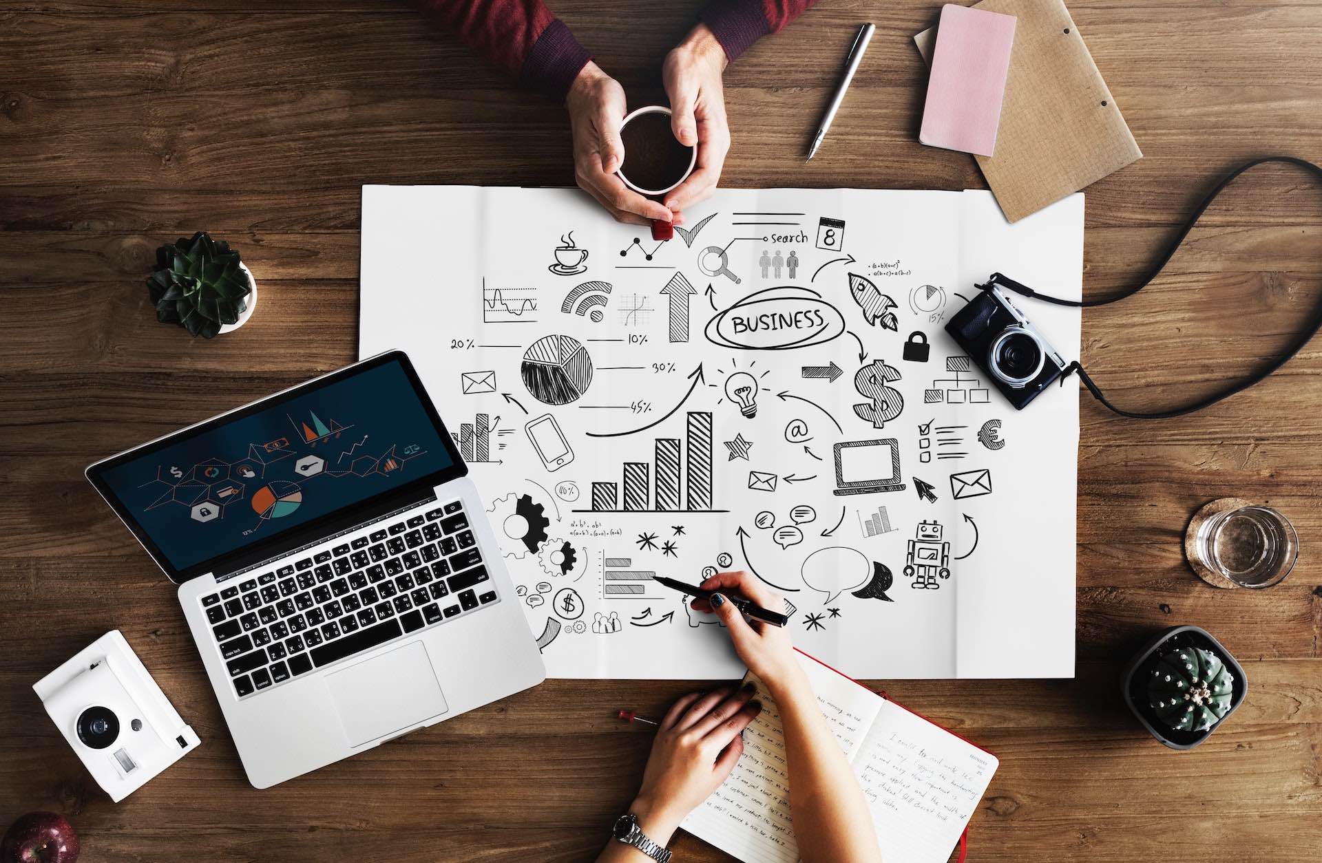 Two people working at desk with laptop and drawings